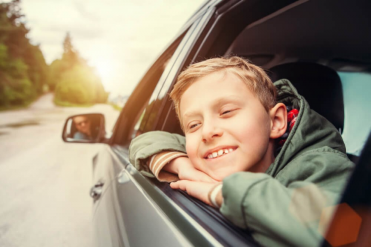 kid with head leaning out of the window of a car