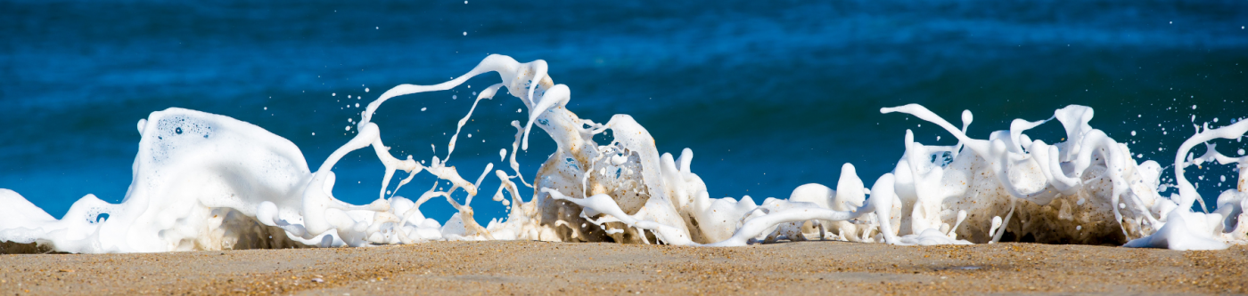 Ocean foam washing up on sand