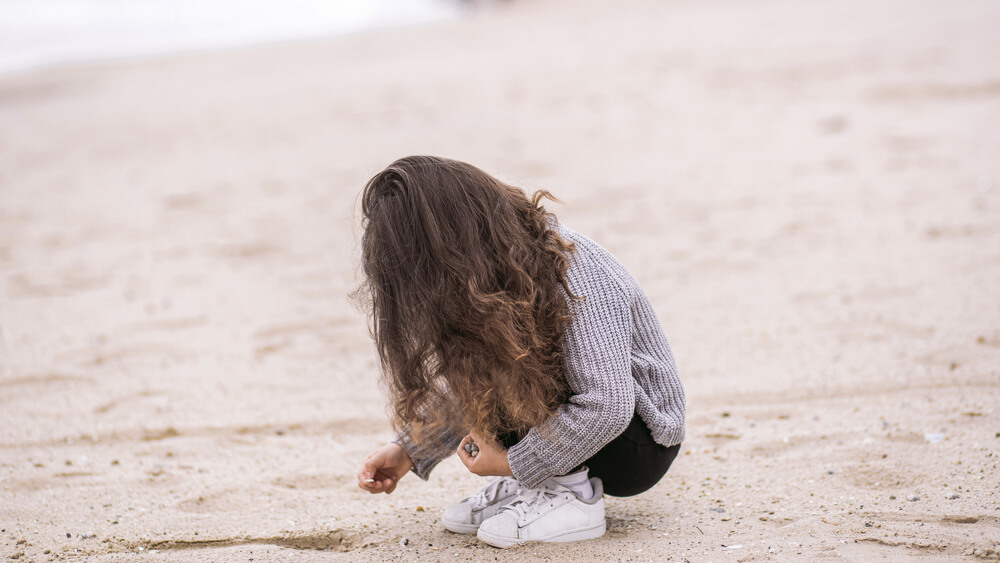 A little kid looking for shells on an Emerald Isle beach during a North Carolina winter vacation.
